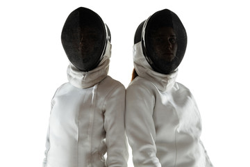Confidence. Teen girls in fencing costumes with swords in hands on white background. Young female...