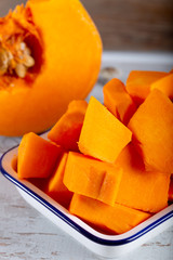 Peeled and chopped pumpkin on wooden background.