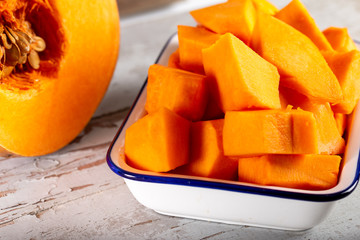 Peeled and chopped pumpkin on wooden background.