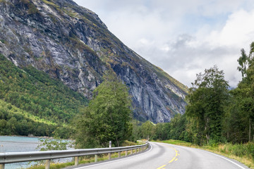 Mountains road near Åndalsnes in Norway, rocky hills and river, scenic nature valley with clouds view. Traveling by car, driving nature tourism. 