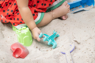 Asian baby girl playing sand outdoor. Kid building sand castle.