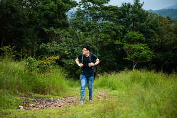 Fototapeta na wymiar Young backpacker with backpack traveling along at forest. Tourist hiking in jungle forest.