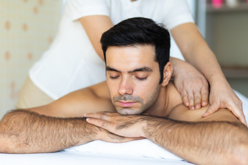 Fototapeta na wymiar Massage, Spa, Health & Wellness Retreats concept. Young handsome man lin in bed and receiving herbal massage by elderly woman Masseur at spa Health & Wellness center