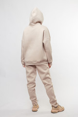Young girl wearing blank and oversize beige long hoody, beige pants, beige sneakers . Standing. Isolated on white background.