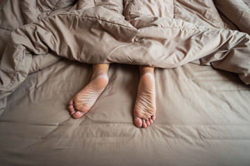 Sleeping girl Stretching your feet out of the blanket in the morning