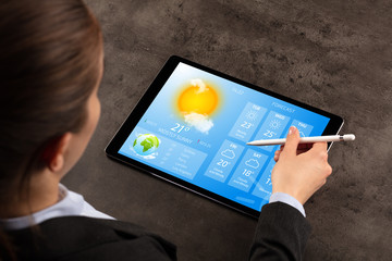 Business woman checking weekly weather forecast on tablet