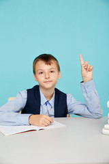 Boy sitting at the table and pointing something up