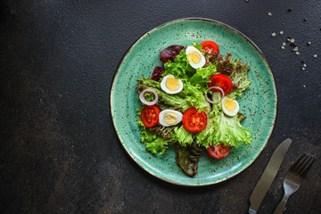 Fototapeta na wymiar healthy salad vegetables, quail eggs (tomato, lettuce and other ingredients) menu concept. food background. top view. copy space