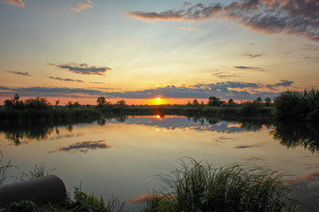 Fototapeta premium Sunset or sunrise on the cloudy sky on lake