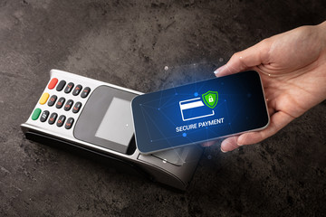 Hand paying on terminal with smartphone in secure payment system