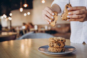 close up photo of delicious and crunchy oatmeal cookies on the backdrop of a cozy restaurant or bakery interior, festive Christmas mood, 4 cookies lying on top of each other