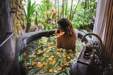 Foto op Canvas Jonge vrouw genieten in buiten luxe spa. Prachtig luxe stenen bad met uitzicht op de jungle. Natuurlijke biologische tropische ingrediënten in het water: gember, limoen, sinaasappel en zeezout. Schoonheidsbehandeling concept © Natallia