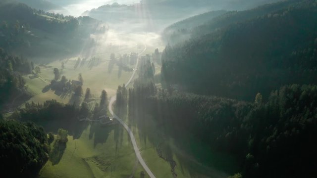 Misty Zell Pfarre village and Valley shadowy aerial view across border with Slovenia, tilt up to Austria skyline.