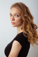 Fototapeta premium Portrait of cute young curly hair woman in the black dress posing in the white studio