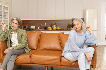 Two unhappy middle-aged Caucasian people sitting apart