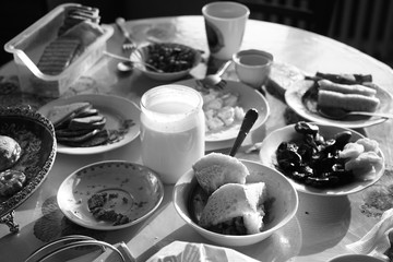 Uncleaned dining table with plates, and mugs and food.