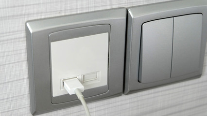 A charging cable plugged into a wall mounted charging port.