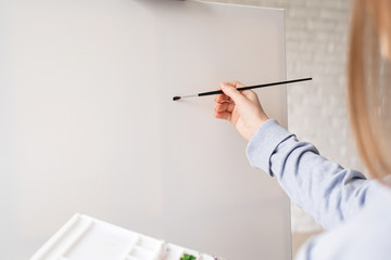 Female artist painting on the canvas in the studio
