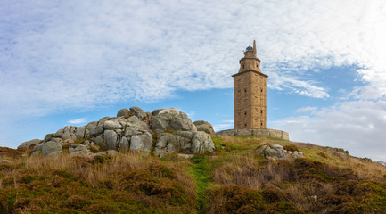 Fototapeta na wymiar The lighthouse of La Coruna is the oldest in the world and is located in northern Spain on the Atlantic. The Hercules tower stands on a rock. The sky is blue with some clouds.