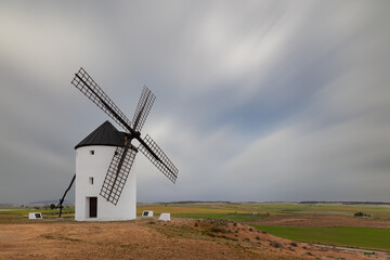 A very well restored historic white windmill in the vast landscape of Castilla in Spain. A long exposure with a nice blue gray cloudy sky.
