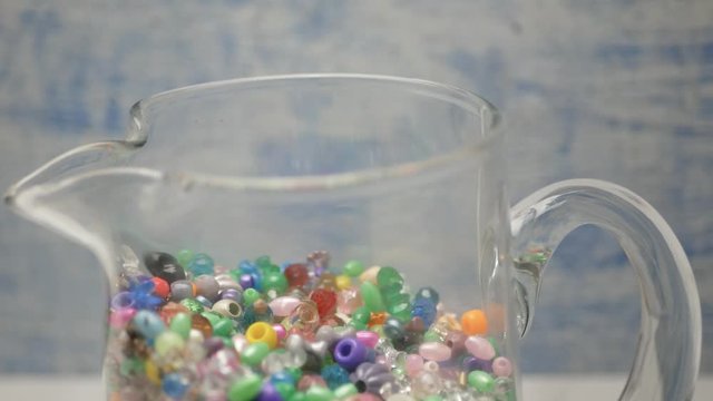 Assorted Beads Pour Into Clear Glass Pitcher