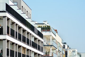 Obraz premium Contemporary residential building exterior in the daylight. Modern apartment buildings on a sunny day with a blue sky. Facade of a modern apartment building