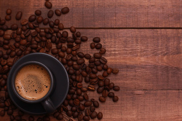 Dark grey cup of coffee and beans on brown wooden table. Coffee shop, espresso, top view, copy space, template
