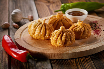 Georgian deep-fried Khinkali dumplings with meat and red pepper, on a wooden cutting board. Traditional dish of Caucasian cuisine. Concept of diet and healthy eating.