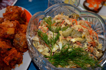  A crystal vase filled with salad stands on a festive tablecloth.