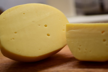 Edam yellow cheese is located on a wooden board.