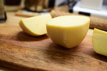 Edam yellow cheese is located on a wooden board.