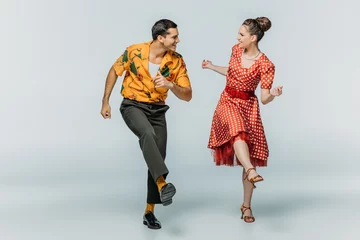 Gordijnen stylish dancers looking at each other while dancing boogie-woogie on grey background © LIGHTFIELD STUDIOS
