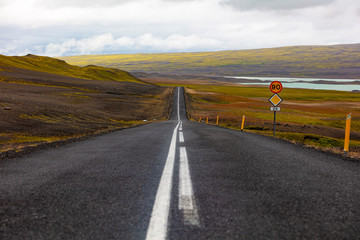 Road marking on highway by sign against sky