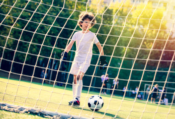 Summer soccer tournament for young kids. football club. emotions and joy of the game. Young goalie. Kids - soccer champion. Boy goalkeeper in football sportswear on stadium with ball. Sport concept.
