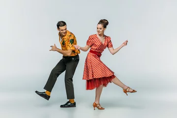 Fototapete Tanzen Young dancers holding hands while dancing boogie-woogie on grey background  © LIGHTFIELD STUDIOS