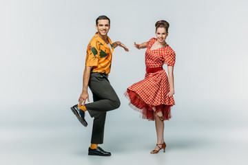 stylish dancers looking at camera while dancing boogie-woogie on grey background