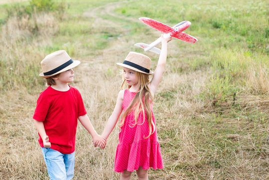 Happy childhood. Concept of dreams and travels. Enjoying nice weekend together. Two happy children boy and girl playing with toy airplane over meadow having fun and smiling.