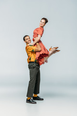stylish dancer holding partner while dancing boogie-woogie on grey background