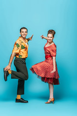 young dancers looking at camera while dancing boogie-woogie on blue background