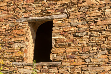 Grunge wooden window on abandoned rural house stone wall closeup