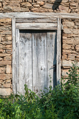 Old weathered wooden rural stone house door closeup in sunny summer day