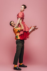 cheerful dancer holding partner while dancing boogie-woogie on pink background
