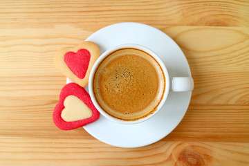 Top view of a cup of espresso coffee with two heart shaped cookies on wooden table