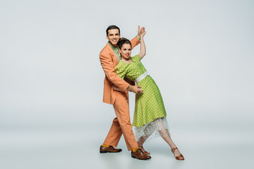 stylish dancers looking at camera while dancing boogie-woogie on grey background