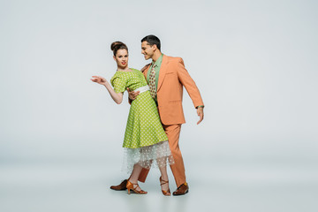 stylish dancers dancing boogie-woogie on grey background