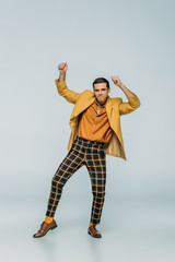 handsome, elegant dancer looking at camera while dancing boogie-woogie on grey background