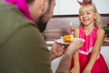 Obraz na płótnie Canvas Young man giving piece of cake to joyful daughter