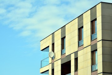 Obraz premium Contemporary residential building exterior in the daylight. Modern apartment buildings on a sunny day with a blue sky. Facade of a modern apartment building