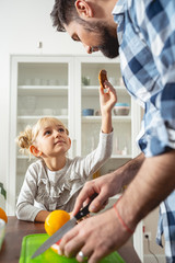 Cute little girl giving father delicious cookie