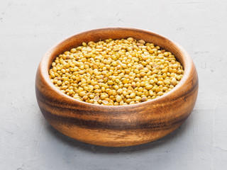 Coriander (Coriandrum sativum) seeds in wooden cup on gray concrete and beige fabric background. Healthy eating concept